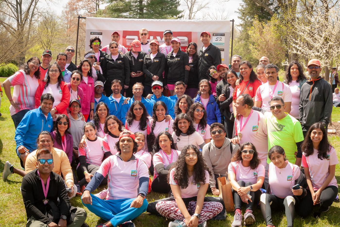Runners in pink shirts in front of an RHWB banner